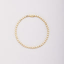 Gold-tone bracelet with round clear stones in bezel settings, laid flat in a closed loop with the clasp at the top.