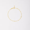 Gold-tone chain bracelet with three round bezel-set stones and small beads, shown laid flat on a light background.