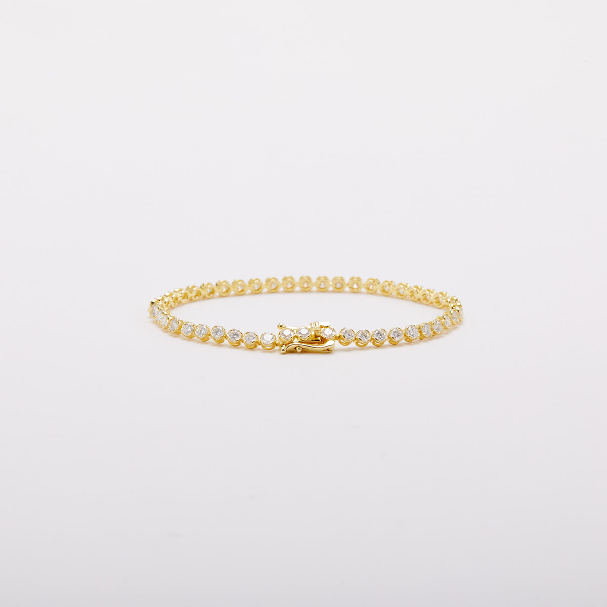 Gold-tone bracelet with a row of round clear stones, viewed at a low angle with the clasp at the front.
