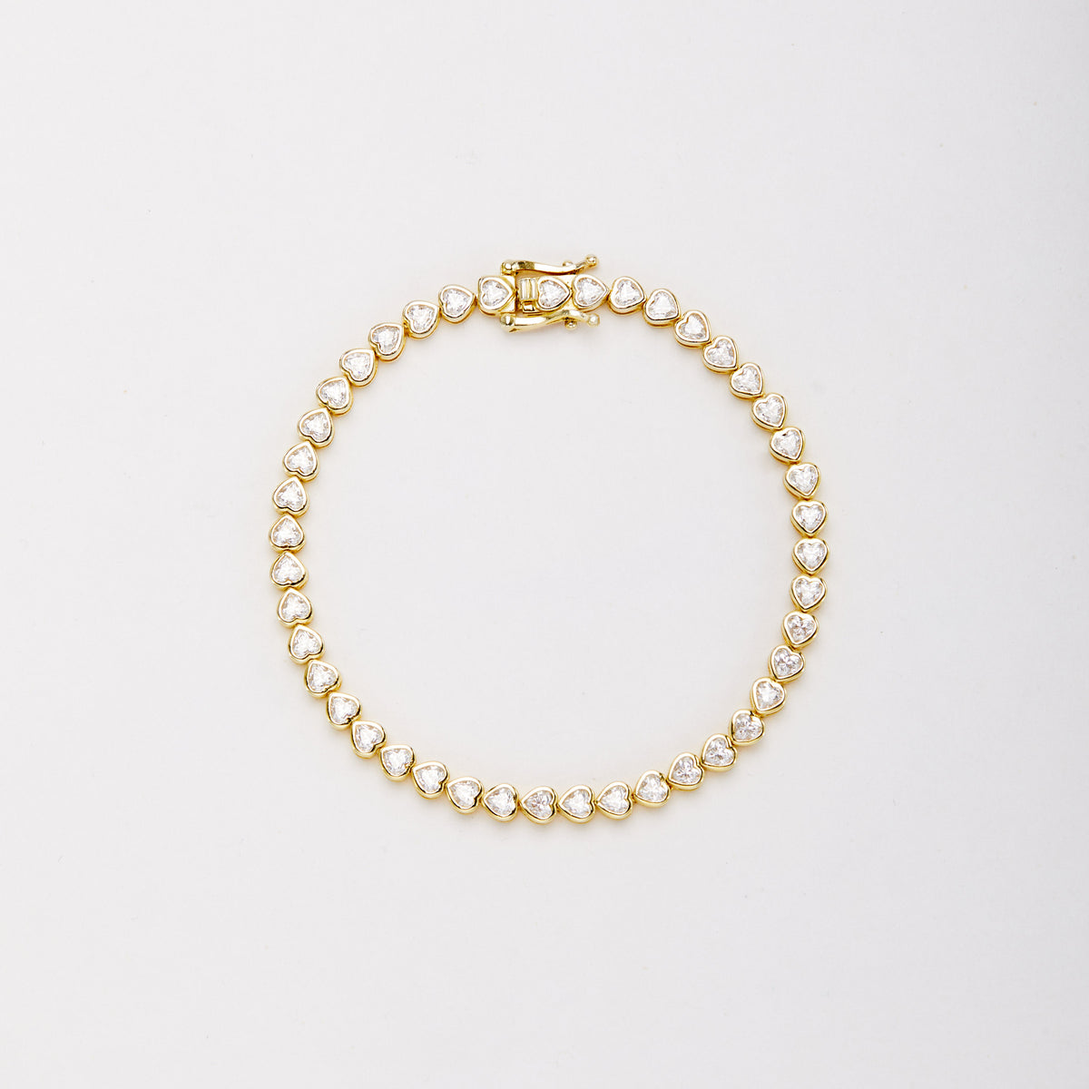 Gold-tone bracelet with heart-shaped clear stones in bezel settings, laid flat in a closed loop with the clasp at the top.