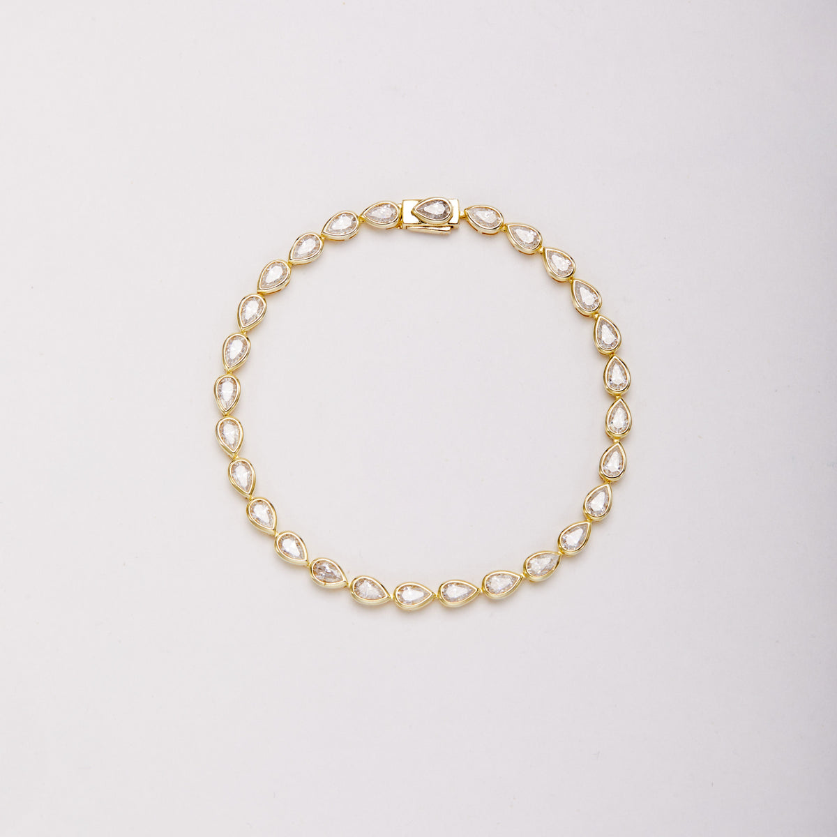 Gold-tone bracelet with pear-shaped bezel-set stones, shown laid flat in a loop on a light background. Main image