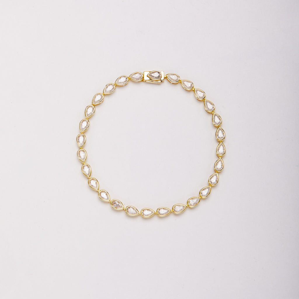 Gold-tone bracelet with pear-shaped bezel-set stones, shown laid flat in a loop on a light background.