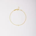 Gold-tone solitaire bracelet with a round bezel-set stone, shown laid flat on a light background.