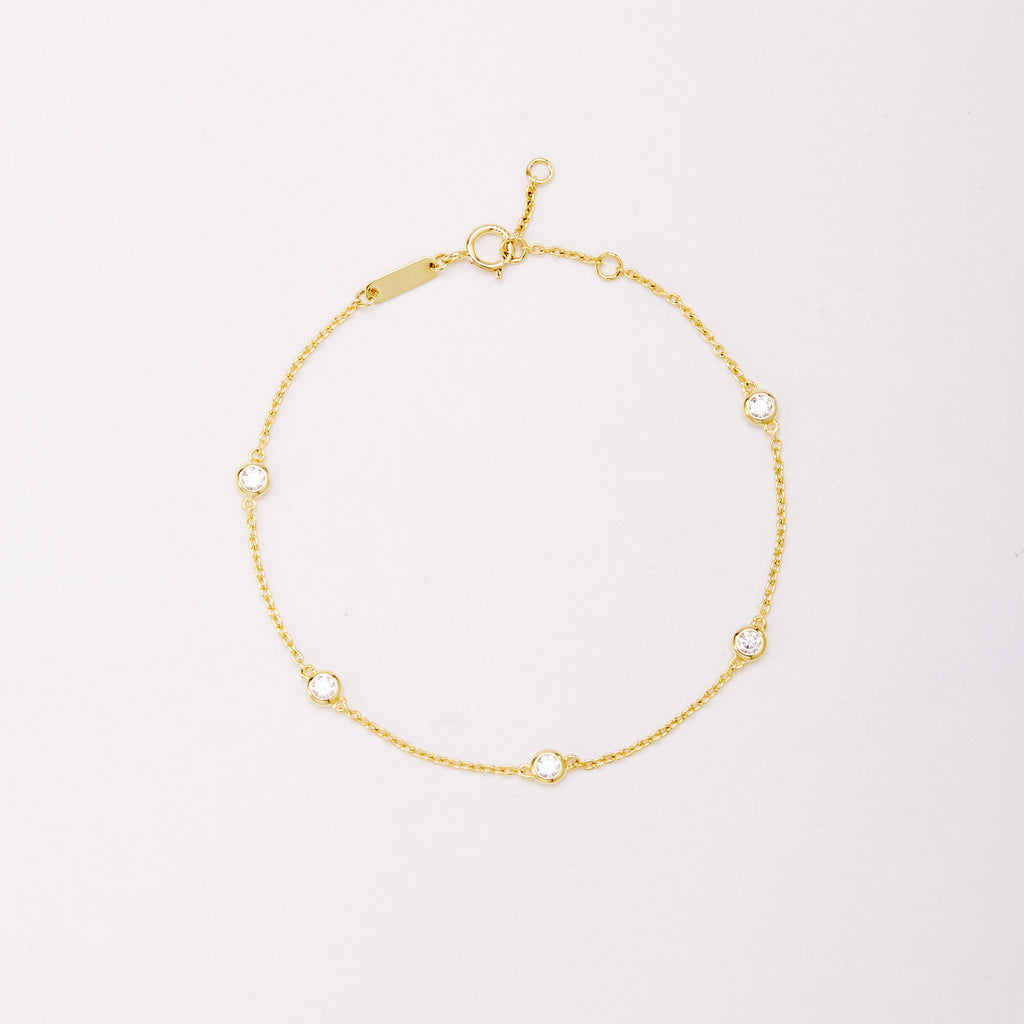 Gold-tone chain bracelet with five round bezel-set stones, shown laid flat on a light background.