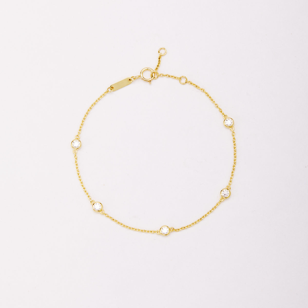 Gold-tone chain bracelet with five round bezel-set stones, shown laid flat on a light background.