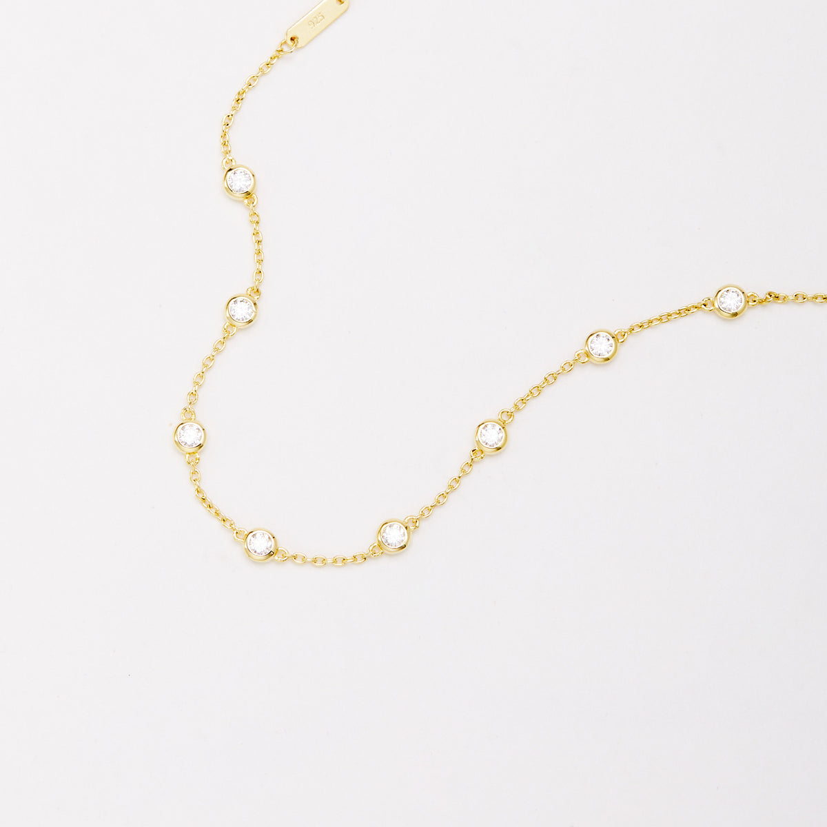 Close-up of round bezel-set stones and connecting links on a gold-tone chain bracelet.