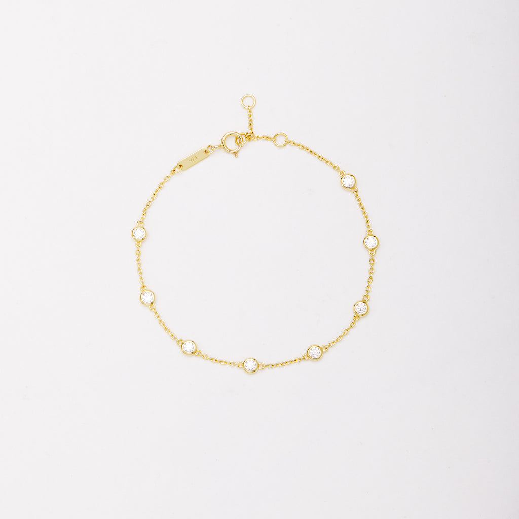 Gold-tone chain bracelet with eight round bezel-set stones, shown laid flat on a light background.